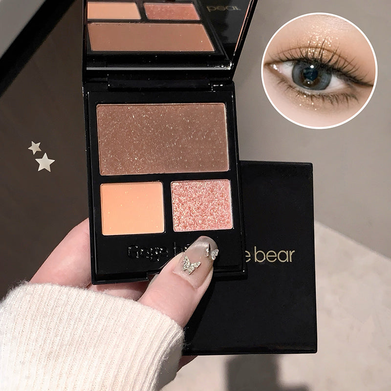 Makeup palette with four shades held by a hand, close-up of eye wearing glittery makeup.