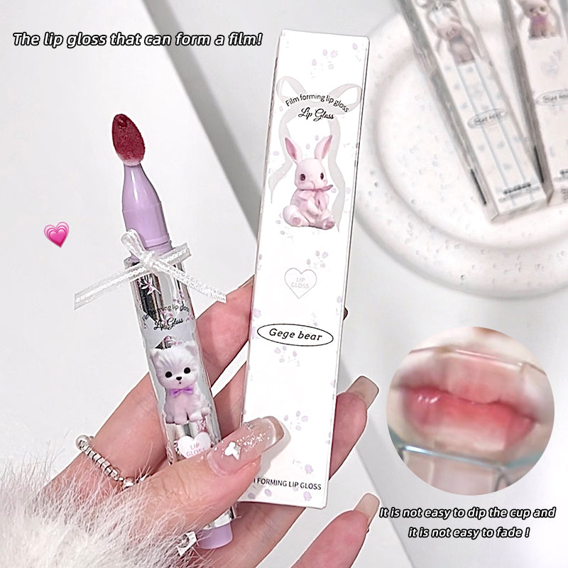 Lip gloss with a cute design held by a hand, accompanied by its packaging and a close-up of the lip gloss on lips.