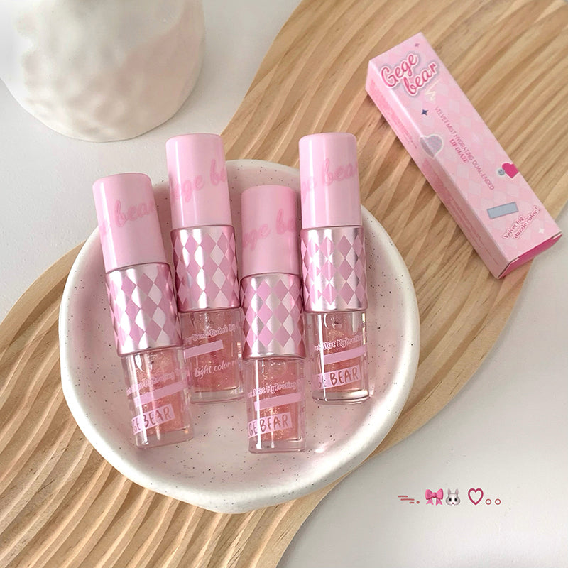 Set of pink lip glosses with a box on a wooden surface