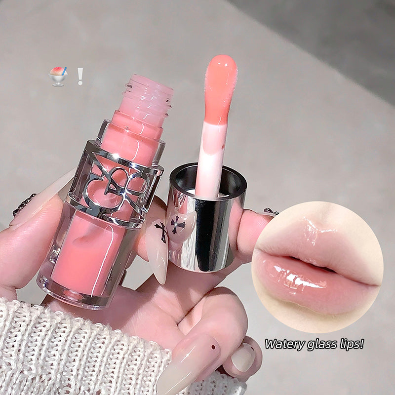 Pink lip gloss with applicator held by a hand, close-up of lips wearing the product.