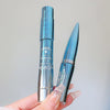 Two blue and silver cosmetic products held by a hand against a light gray background
