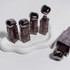 Set of nail polish bottles with metallic caps on a white stand, with 'Gege' branding visible.