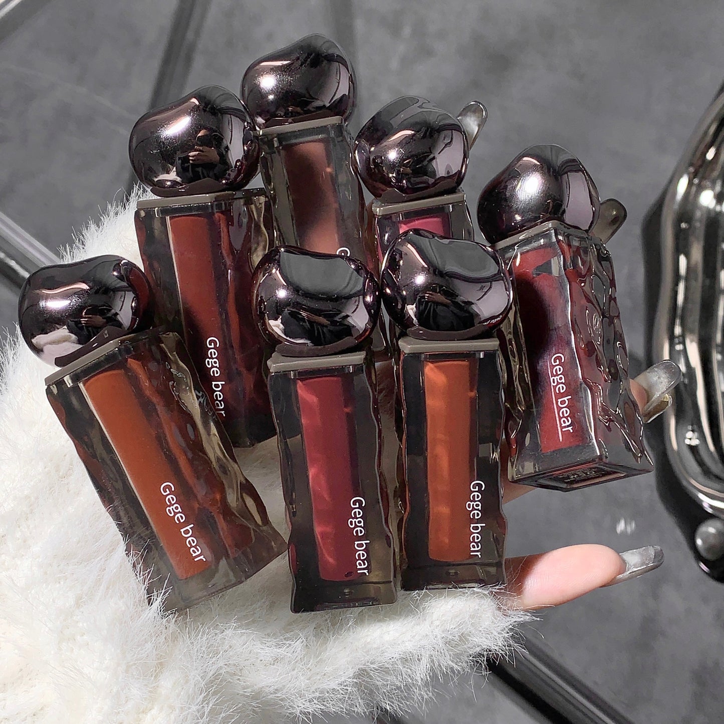 Set of Gege bear lip glosses held by a hand with a textured background