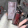 Lip gloss with packaging labeled 'Gegebear' held by a hand against a blurred background.