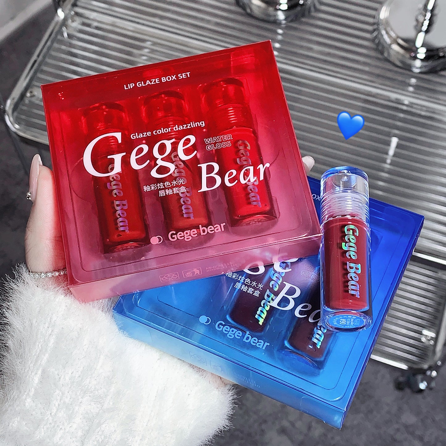 Gege Bear lip glaze set with a red box and blue tray on a reflective surface.