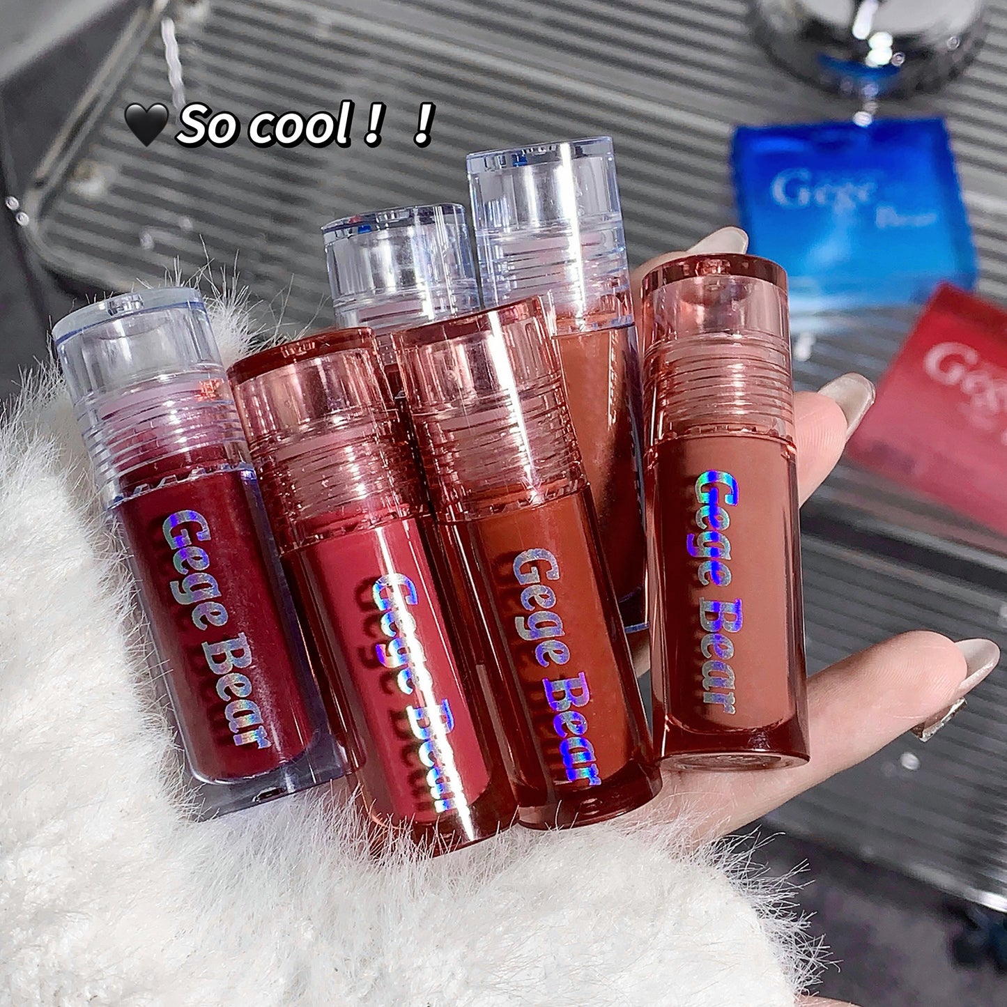 Hand holding multiple Gege Bear lip glosses with a blurred background