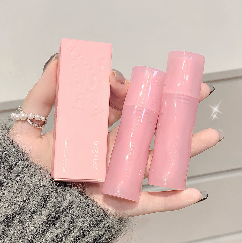 Pink skincare product set held by a hand against a neutral background