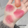 Hand with pink lipstick swatches and a lip gloss applicator on a neutral background