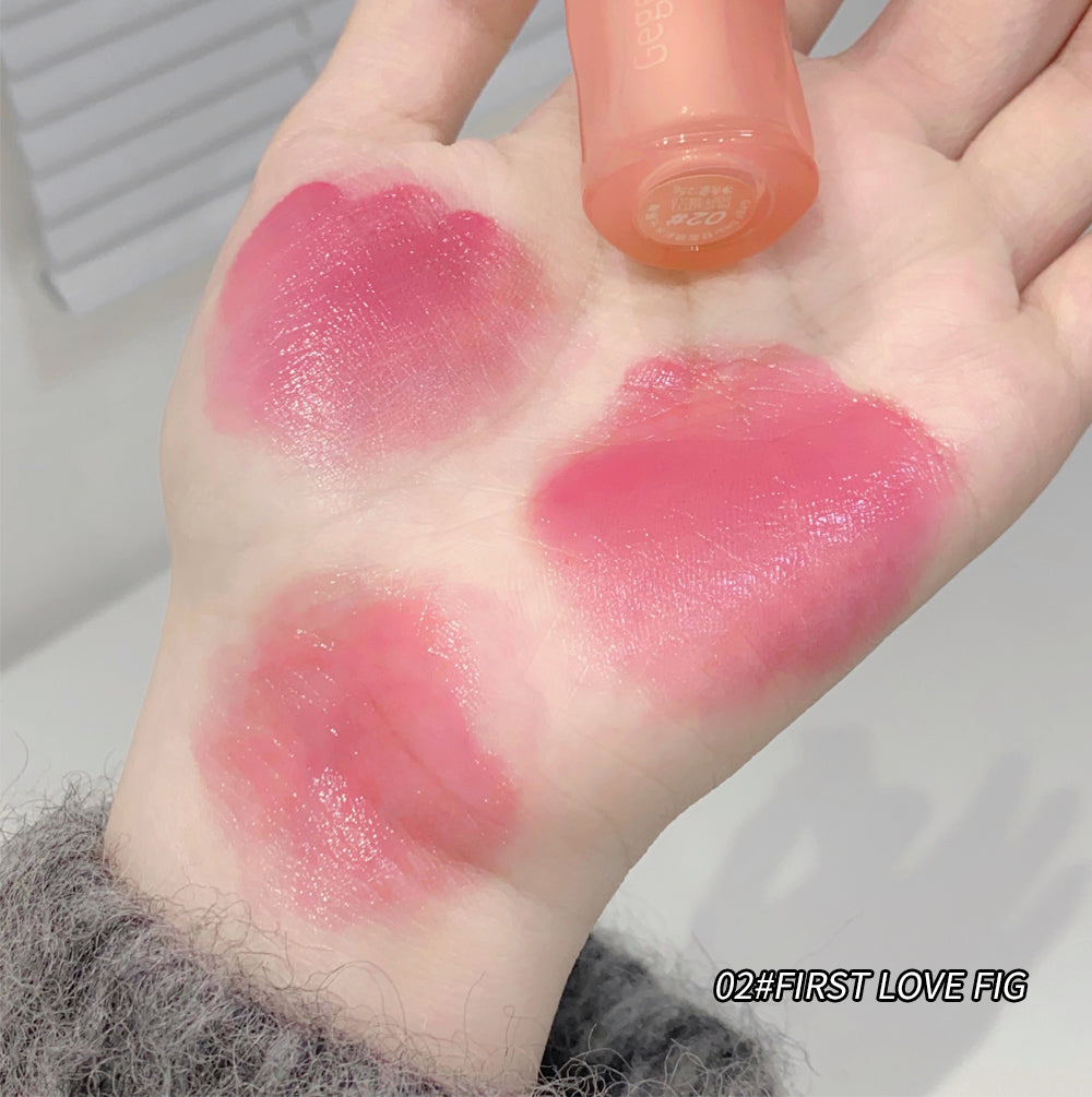 Hand with pink lipstick swatches and a lip gloss applicator on a neutral background