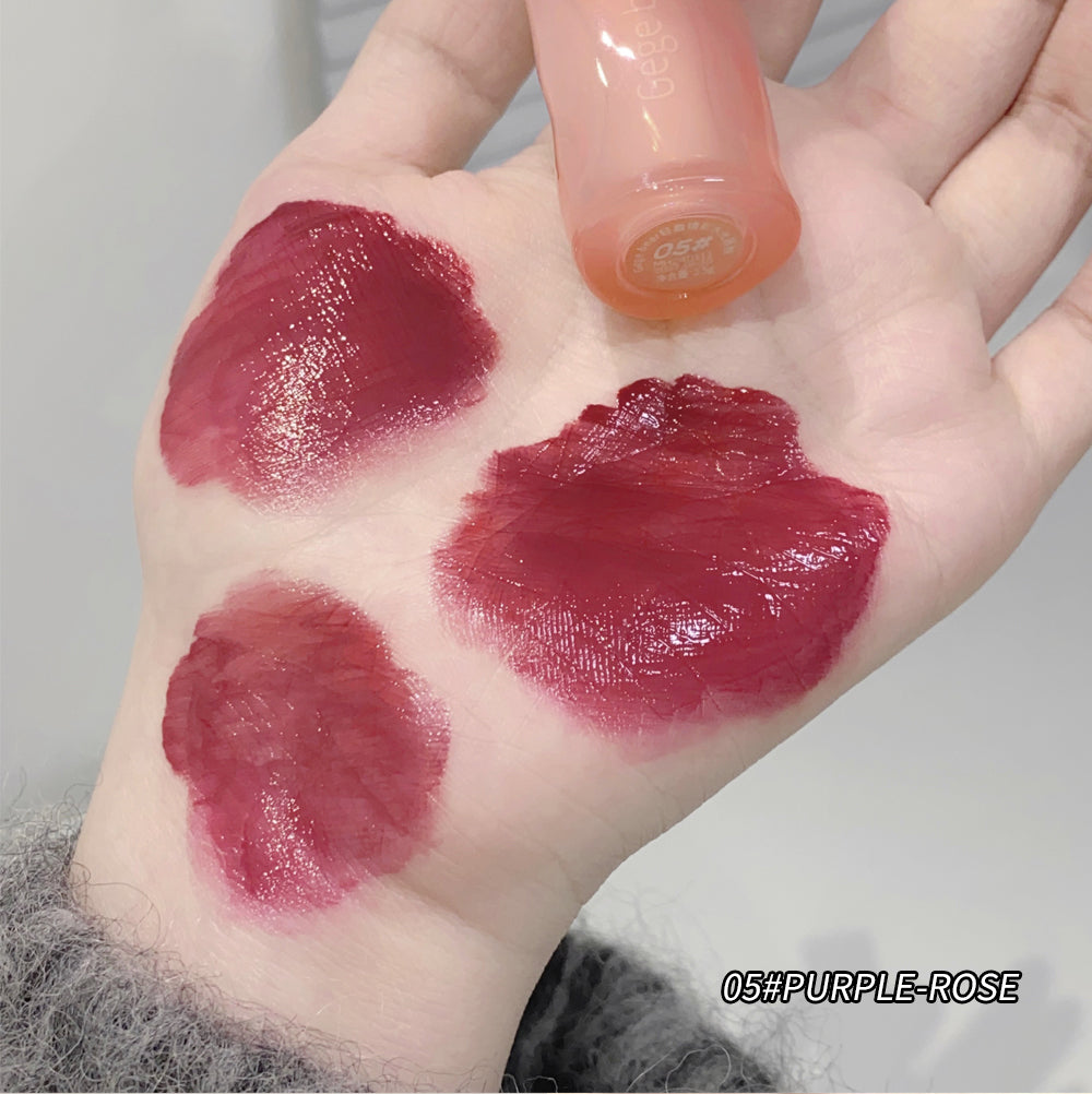 Hand with three swatches of 'Purple Rose' lipstick shade on a neutral background