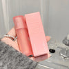 Pink cosmetic bottle and packaging held by a hand with a blurred background