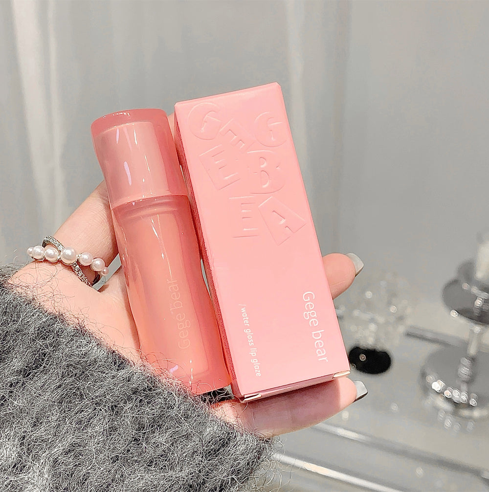 Pink cosmetic bottle and packaging held by a hand with a blurred background