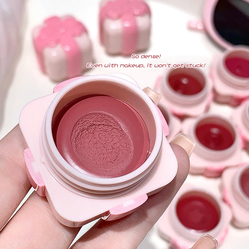 Pink makeup product with a close-up of the texture, surrounded by more products.