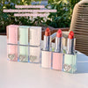 Set of lipsticks in clear cases with heart designs on a light surface.