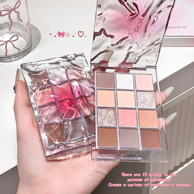 Makeup palette with pink and gold design held by a hand, with a blurred background.
