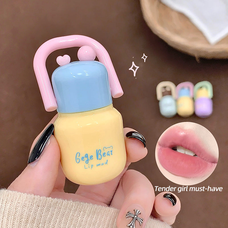 Small bottle-shaped product with pink top and yellow body held by a hand, with inset images of lips and hair clips.