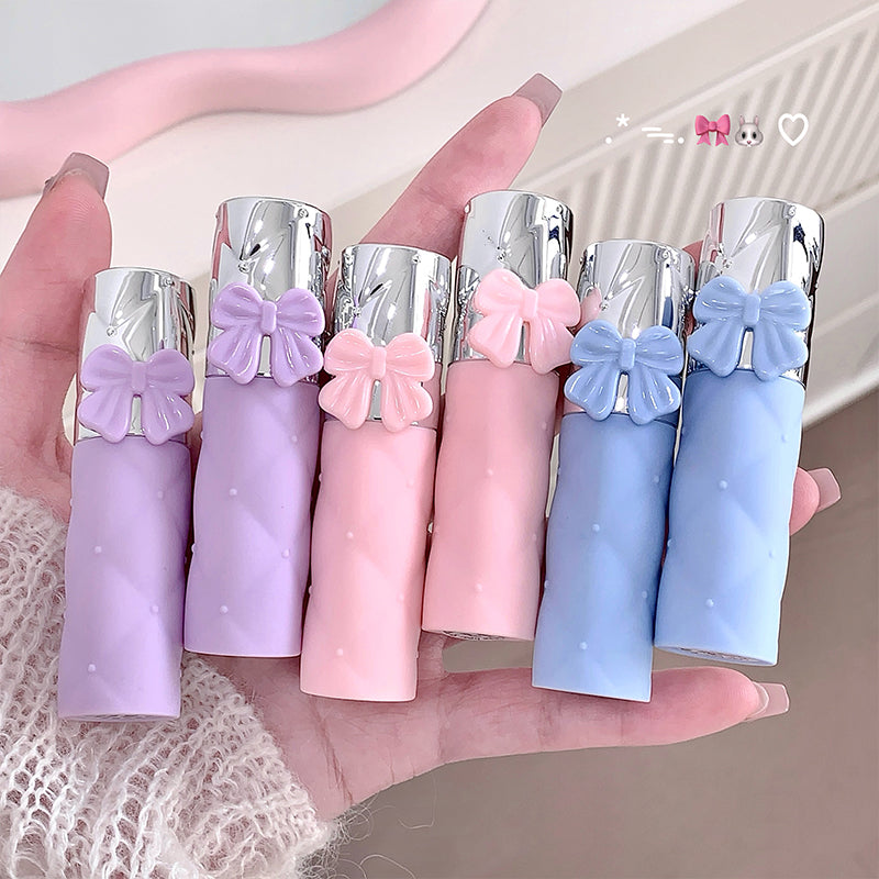 Set of colorful lip balms with bow decorations held in a hand.