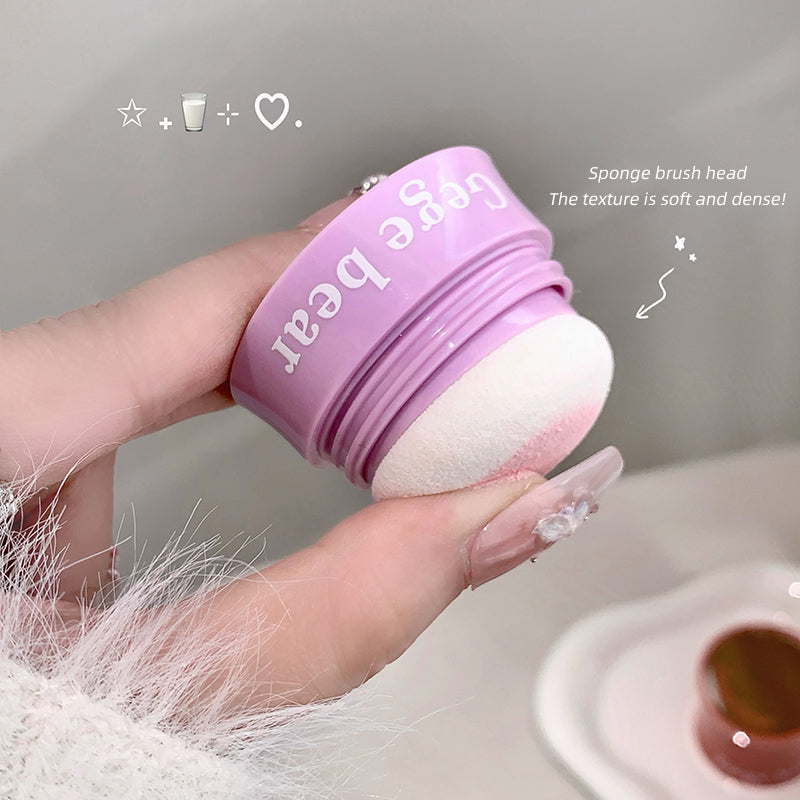 Purple sponge brush head held by a hand with a neutral background