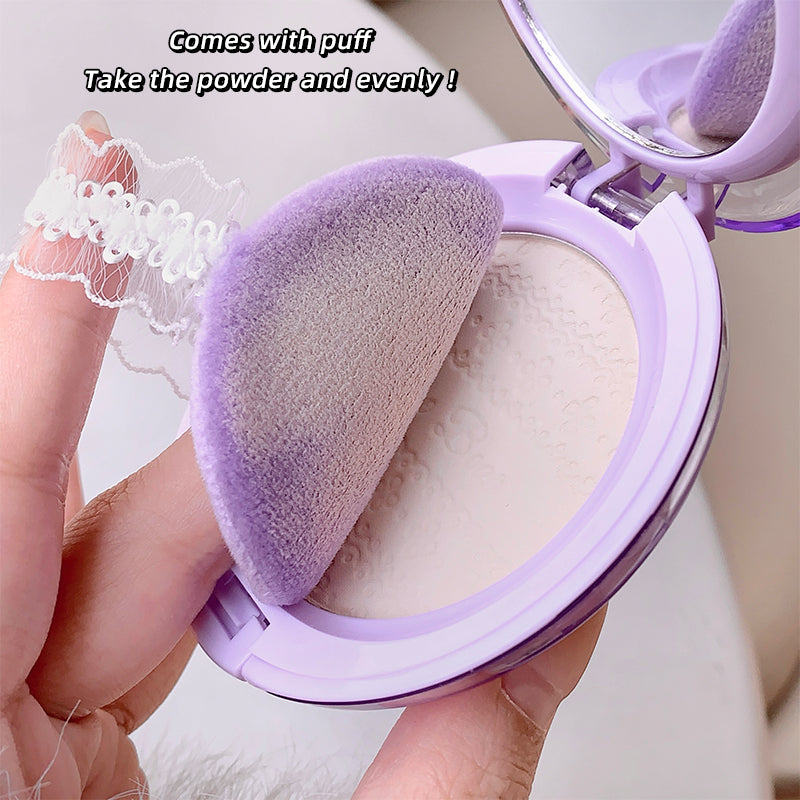 Makeup powder compact with purple sponge puff held by a hand.