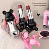Two bear-shaped lipsticks with pendant attachments held by a person.