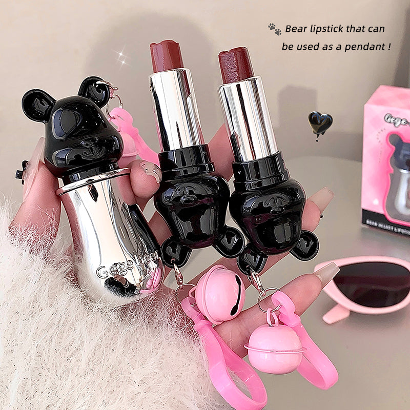 Two bear-shaped lipsticks with pendant attachments held by a person.