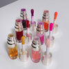 Collection of lip glosses with applicators on a white surface