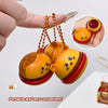 Three small, colorful toy bells shaped like hamburgers held by a hand.