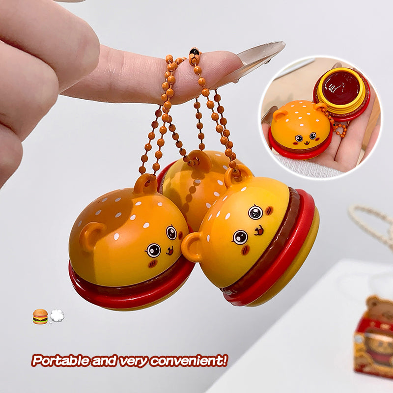 Three small, colorful toy bells shaped like hamburgers held by a hand.