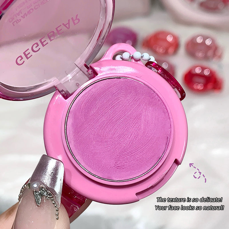 Pink makeup compact with mirror, held by a hand, on a blurred background.