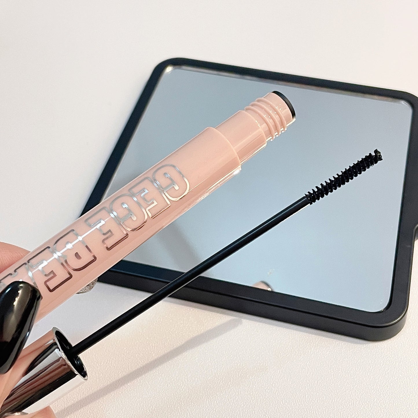 Rose gold brow pencil with black bristle tip against a light background