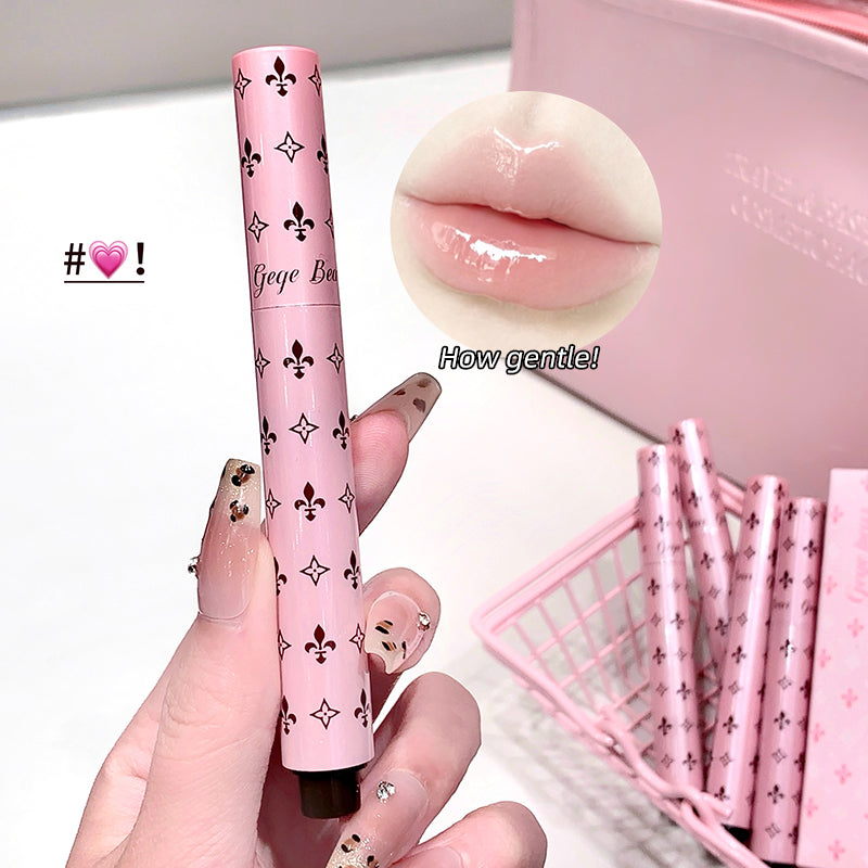 Pink lip balm with decorative design held by a hand, close-up of lips, and pink packaging in the background.