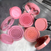 Pink makeup compacts with open lids on a textured surface