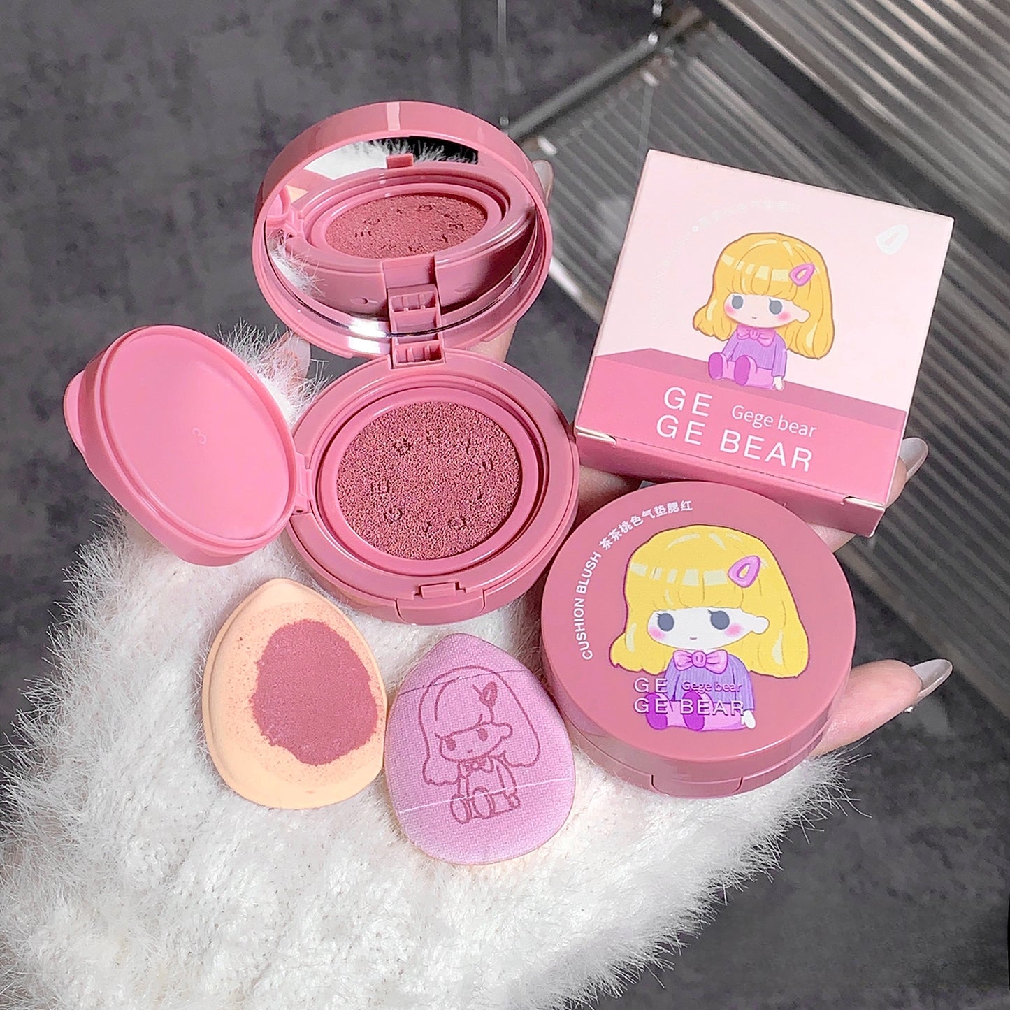 Makeup compact with pink lid andGE GE BEAR branding on a white surface.