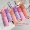 Set of Gege bear lip balms in various colors held by a hand.