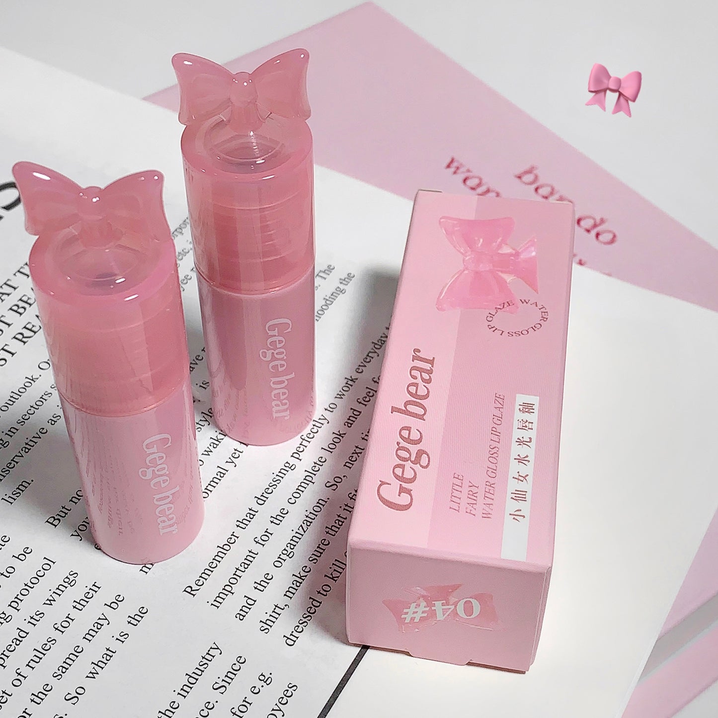 Pink lip gloss with butterfly design and packaging on a white surface.