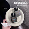 Three 'GEGE BEAR' skincare products on a white plate with a hand holding angel wings, against a dark background.