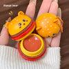 Three small, colorful hamburger-shaped containers held in hands with a brown background.