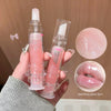Hand holding a transparent lip gloss with pink liquid, showing close-up details on a beige background.