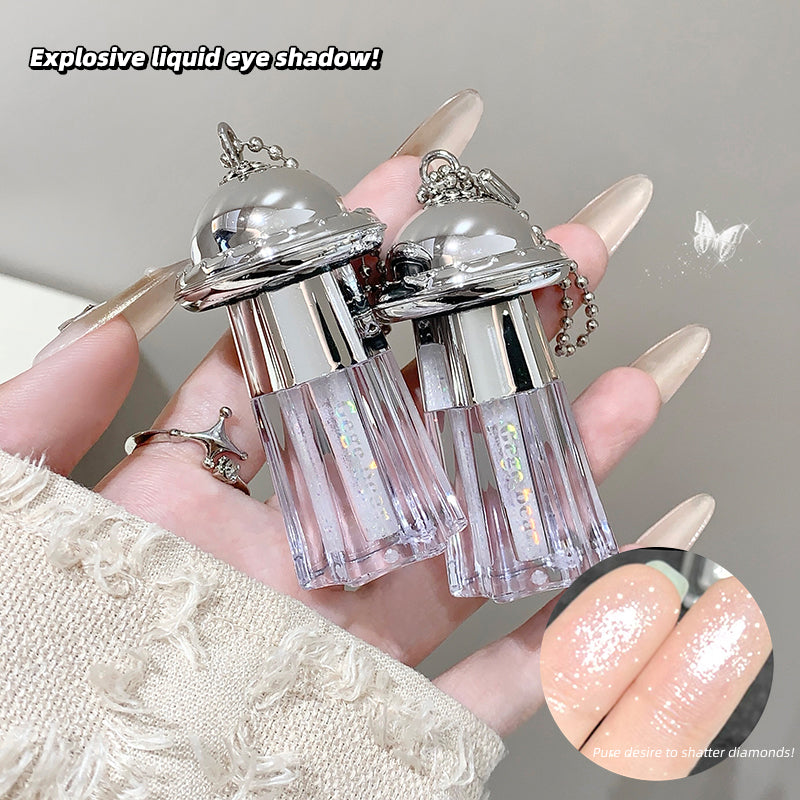 Two small bottles of liquid eye shadow held by a hand with decorative nails.