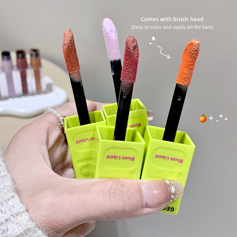 Hand holding a green holder with makeup brushes, including a brush head, against a blurred background.