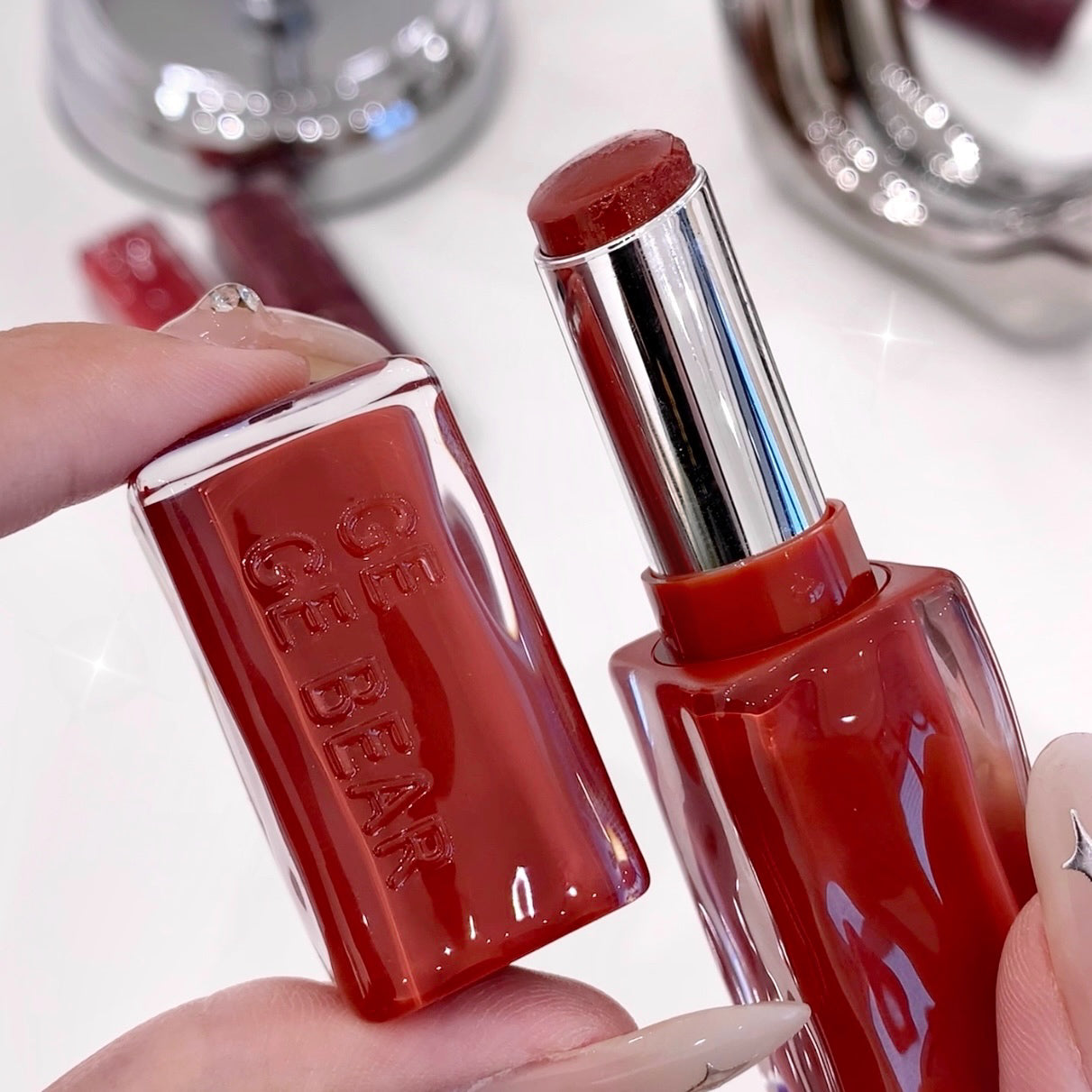 Red lipstick held by a hand with a blurred background