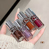 Hand holding four nail polish bottles with metallic caps.