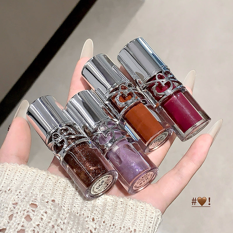Hand holding four nail polish bottles with metallic caps.