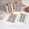 Four trays of false eyelashes on a white surface with a mug and lace doily.