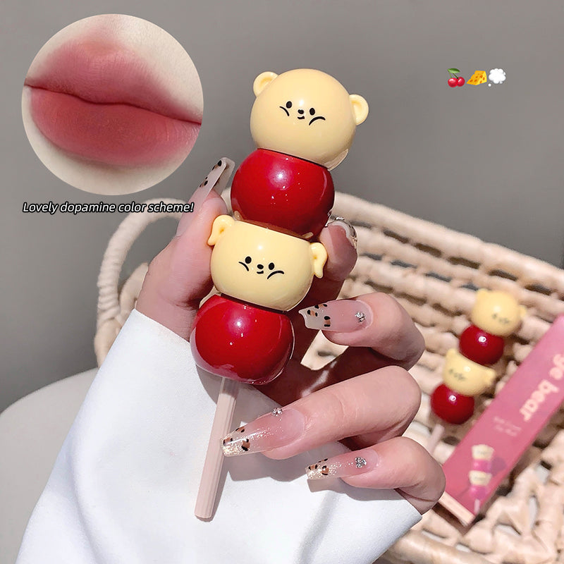 Lip balm with bear design held by a hand, close-up of lips and product packaging.