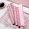 Pink and black patterned items on a pink wire basket with a cup of coffee in the background.