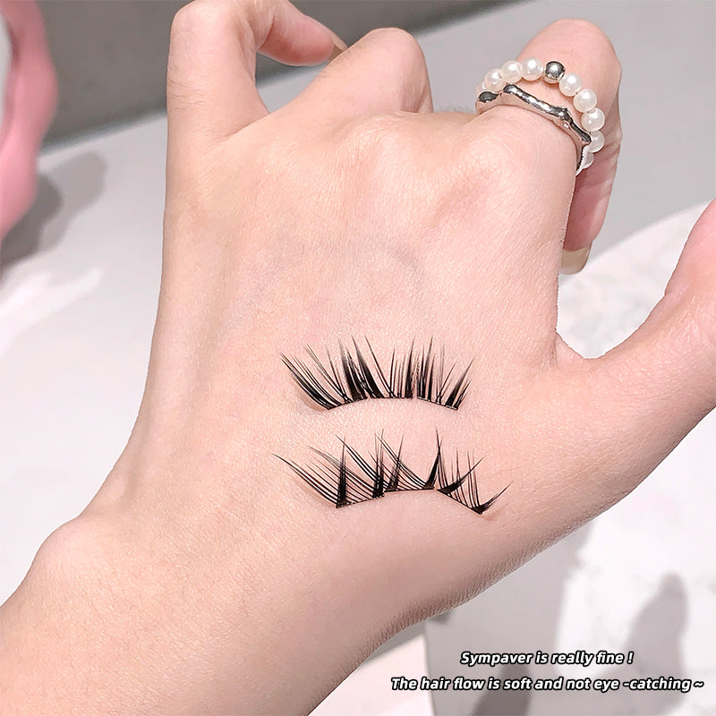 False eyelashes being held between fingers with a blurred background