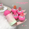 Pink lip balm with sponge applicators on a hand, with text indicating color options.
