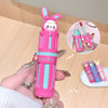 Pink and blue pen-shaped container with a bear design held by a hand on a beige background.