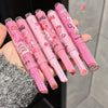 Set of pink pens with cartoon designs held by a hand against a neutral background